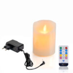 De Oplaadbare LED wax kaars met bewegende vlam D 7,5 X 10 CM - warm wit wordt getoond naast een zwarte adapter en een witte afstandsbediening met kleurrijke knoppen.