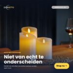 De set van 4 oplaadbare LED-waskaarsen van DORSETTO, met een warme gele gloed, staat op een tafel naast een glas wijn. Op de wazige achtergrond zie je Nederlandse tekst en een knop met de tekst „Shop nu”.