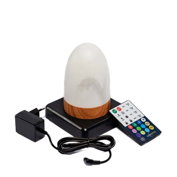 De DORSETTO tafellamp, een ovale, marmeren wit-grijze oplaadbare lamp met houtlook voet, staat op een zwarte mat met een zwarte adapter en kleurrijke afstandsbediening; hij is waterdicht en gaat tot 105 uur mee.