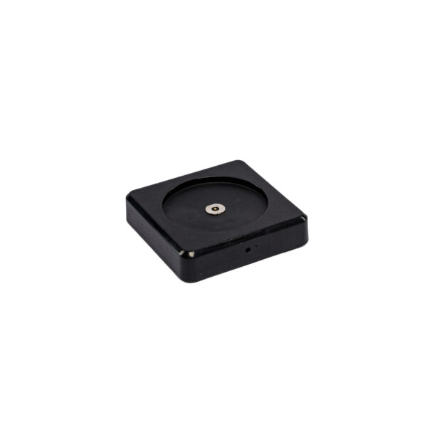 Een klein, vierkant zwart apparaat met afgeronde hoeken en een centrale inkeping rust op een witte achtergrond - de perfecte compacte toevoeging aan je Oplaadstation DORSETTO voor 1 stuks oplaadbare LED tafellamp opstelling.
