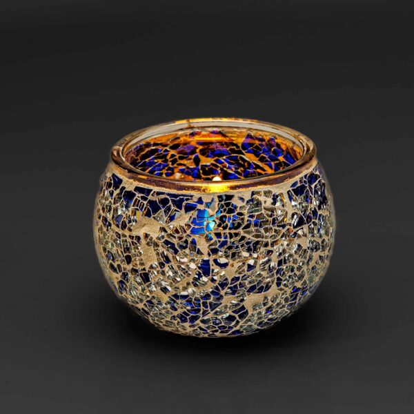 Theelichthouder 9 cm DORSETTO donker blauw is een ronde glazen kandelaar met een mozaïekpatroon van blauwe en zilveren scherven tegen een donkere achtergrond.