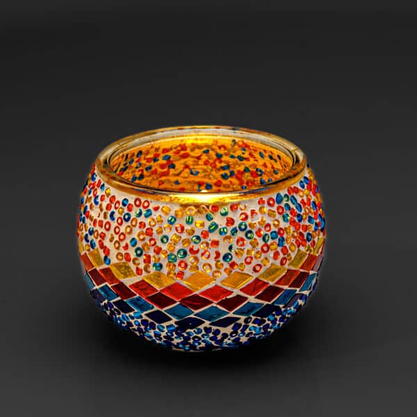 Theelichthouder 3 colormix 9 CM Dorsetto is een ronde kandelaar van mozaïekglas, versierd met rode, blauwe, gele en oranje kralen en tegeltjes. De levendige patronen weerkaatsen het licht prachtig tegen een donkere achtergrond.