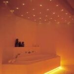 Een modern bad in een warm verlichte badkamer, versterkt door de betoverende LED Sterrenhemel (400 sterren) met 4,5 meter lange glasvezeldraden aan het plafond, creƫert een ontspannen en gezellige sfeer.